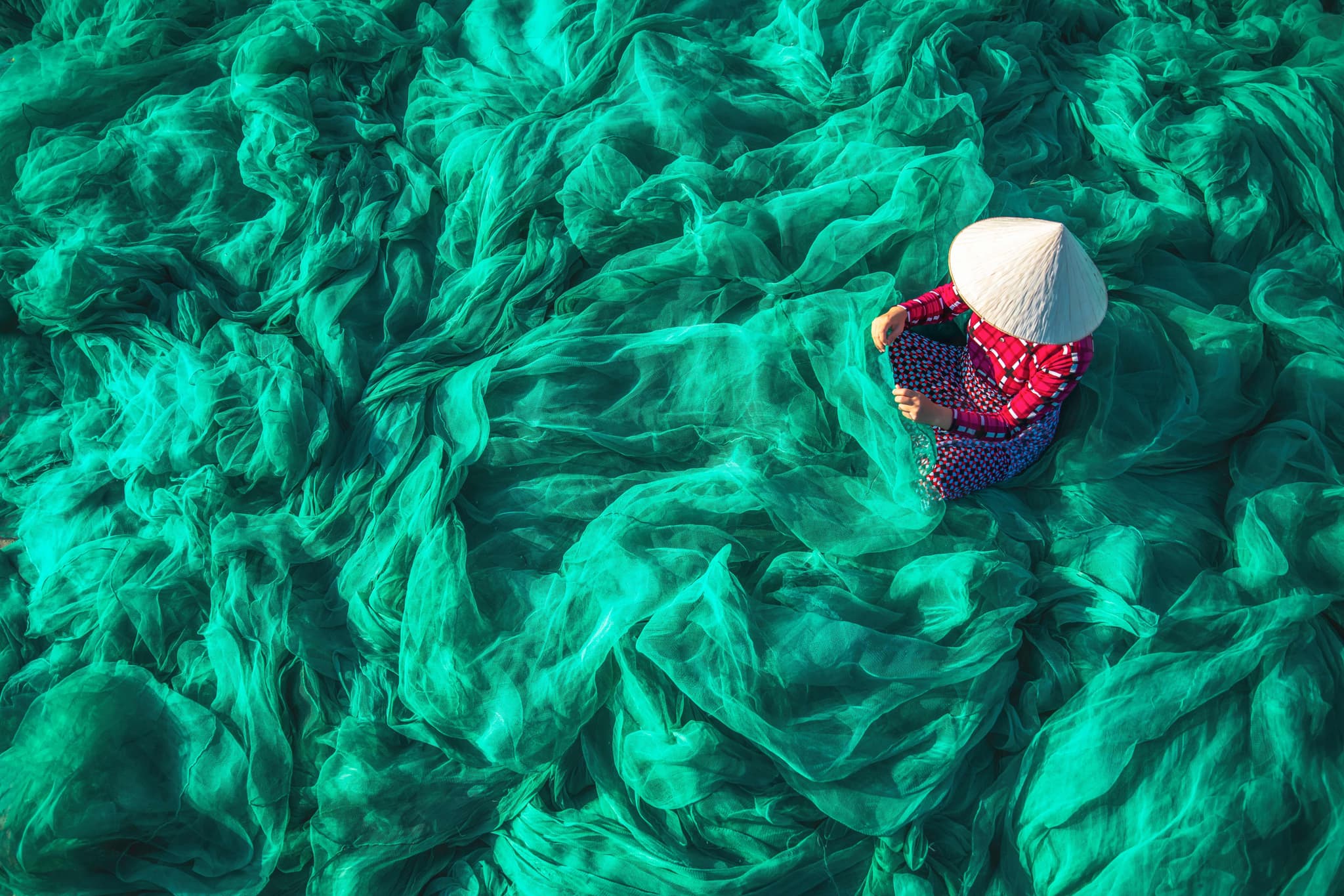 Vietnamese woman repairing fishing nets