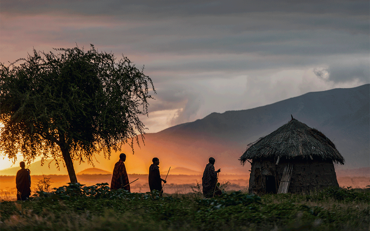 Maasai family walking at sunrise to their traditional house in Arusha, Tanzania
