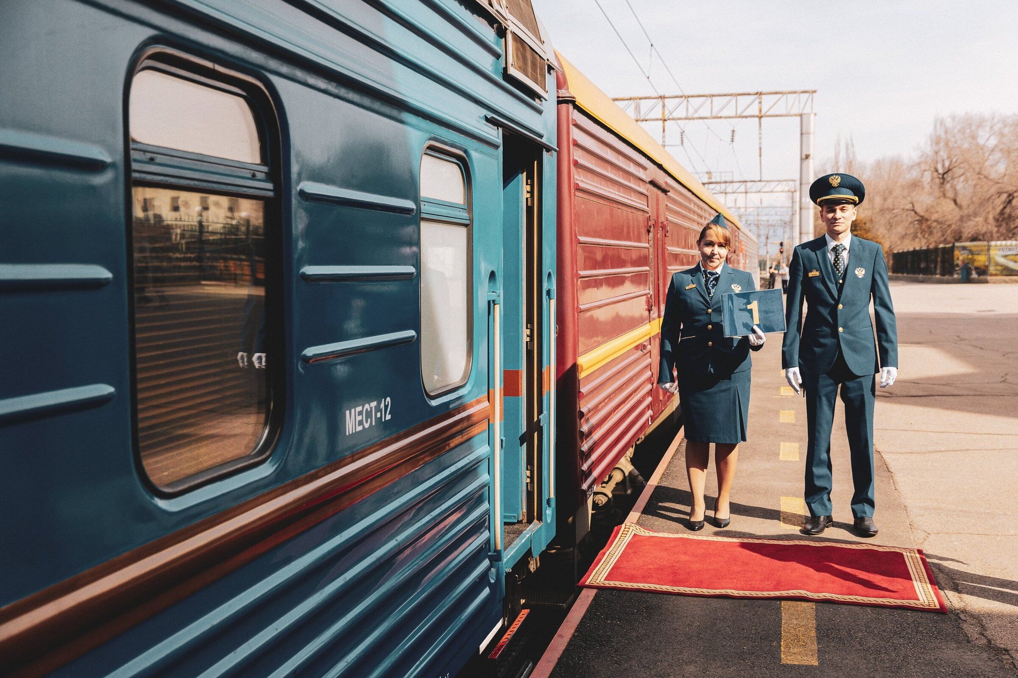 A picture of a luxury train and a pair of staff standing next to the train door