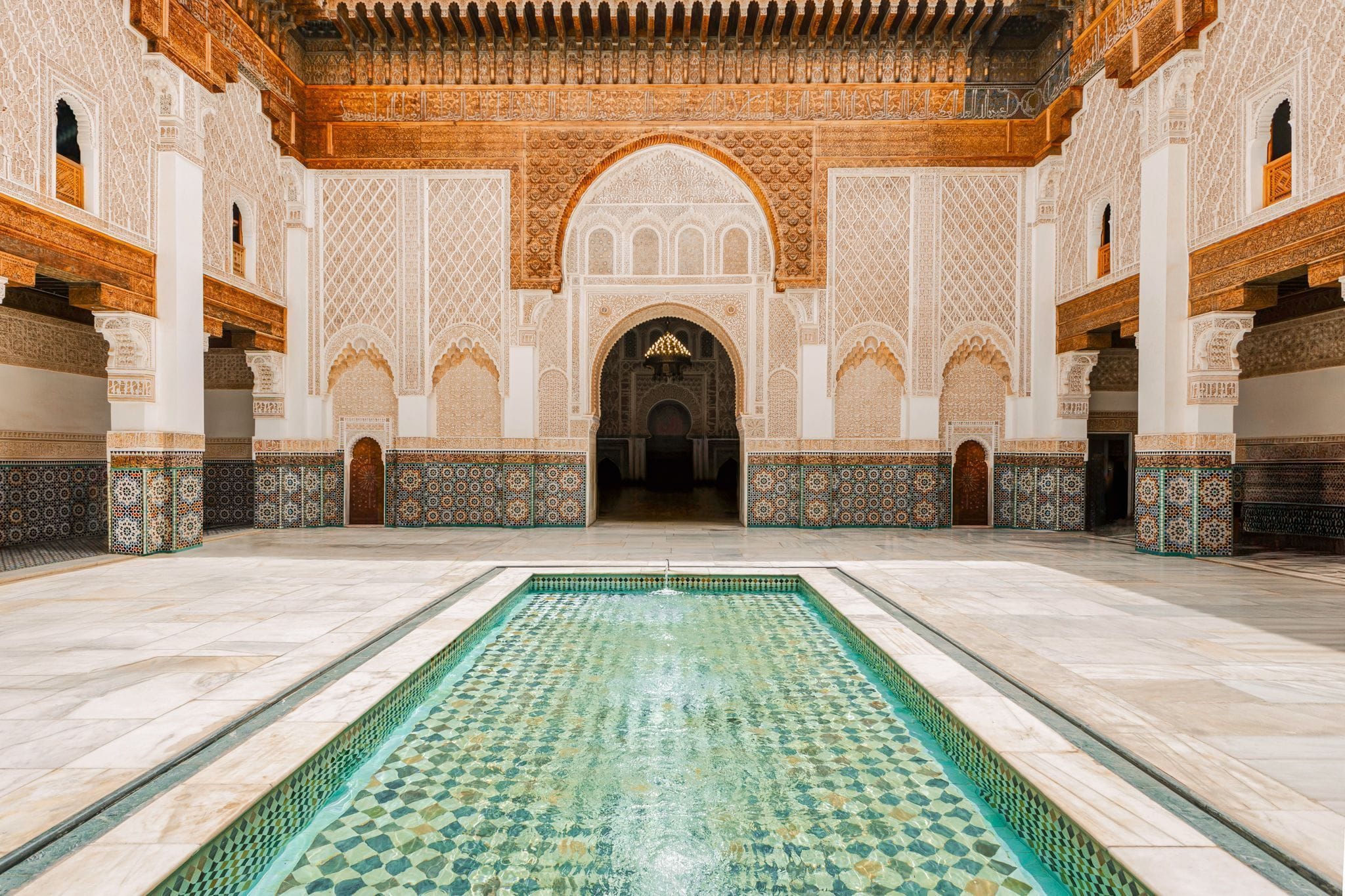 Ben youssef madrasa courtyard with intricate tile mosaics and water pool in Marrakech, Morocco