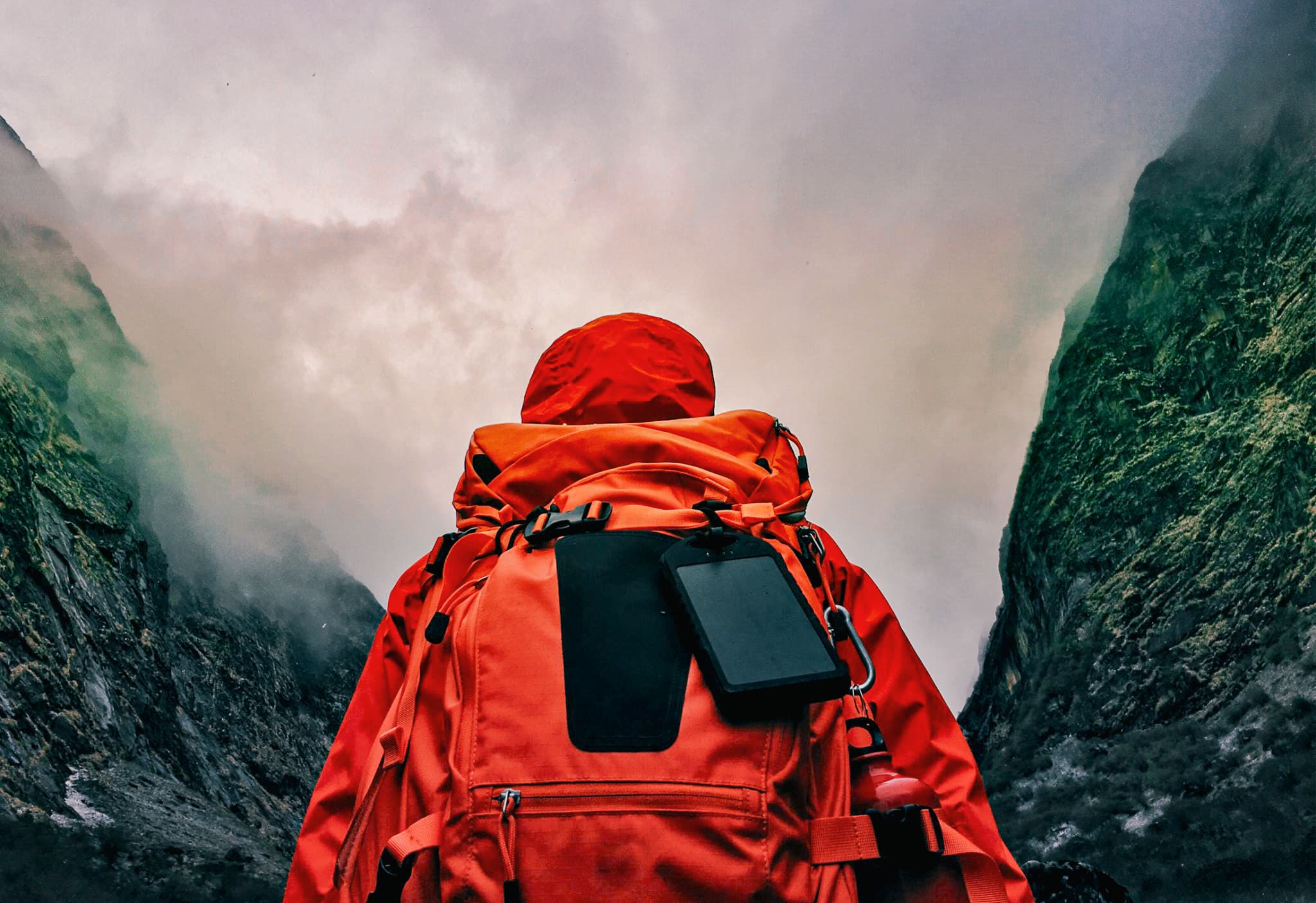 Person standing with their back to the camera with foggy mountains in the background