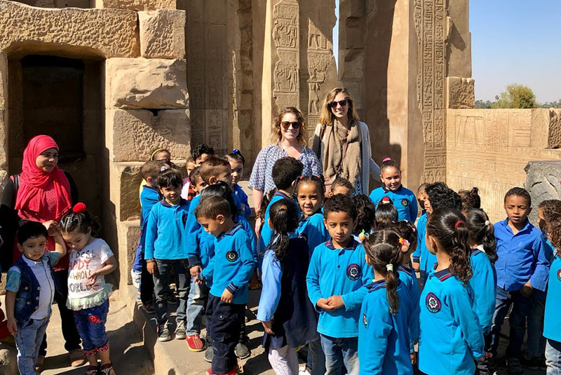 Schoolchildren gather for a photo with travelers at a temple in Egypt