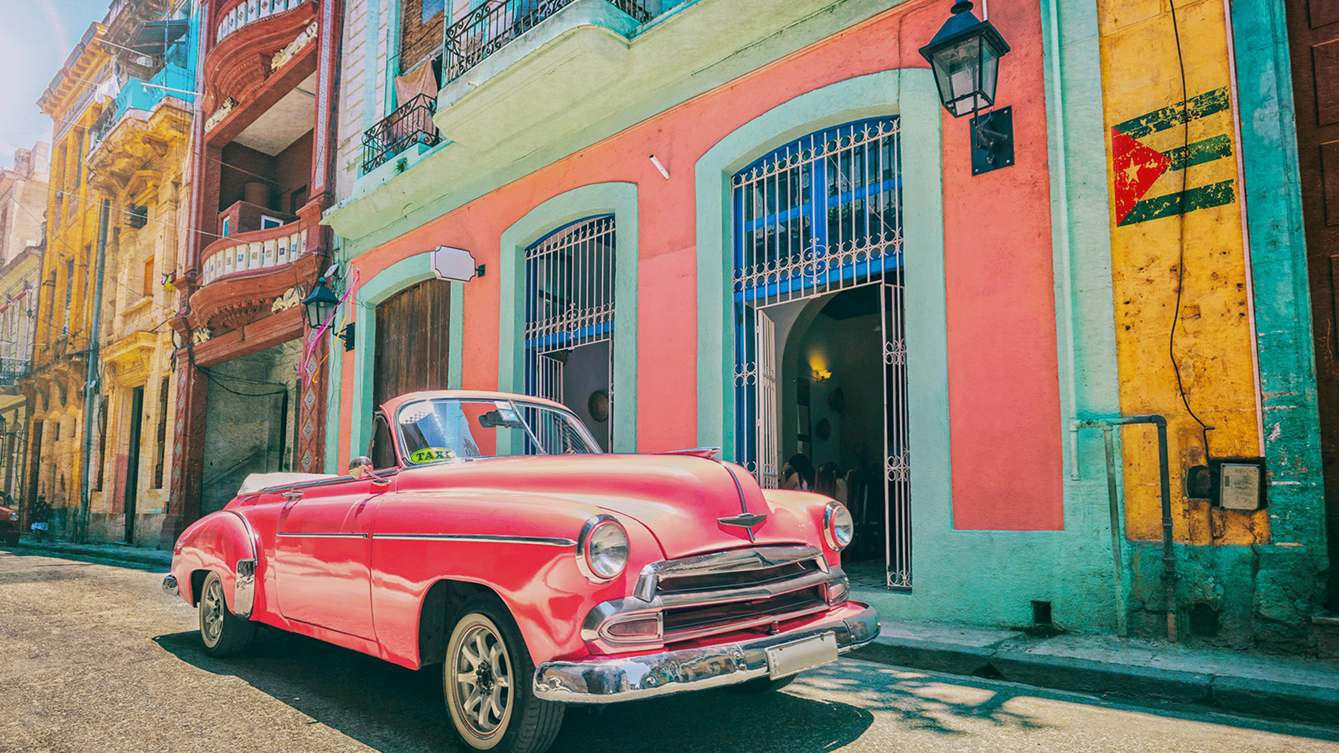 Classic pink convertible car parked on a vibrant street in Havana, a popular sight when traveling to Cuba.