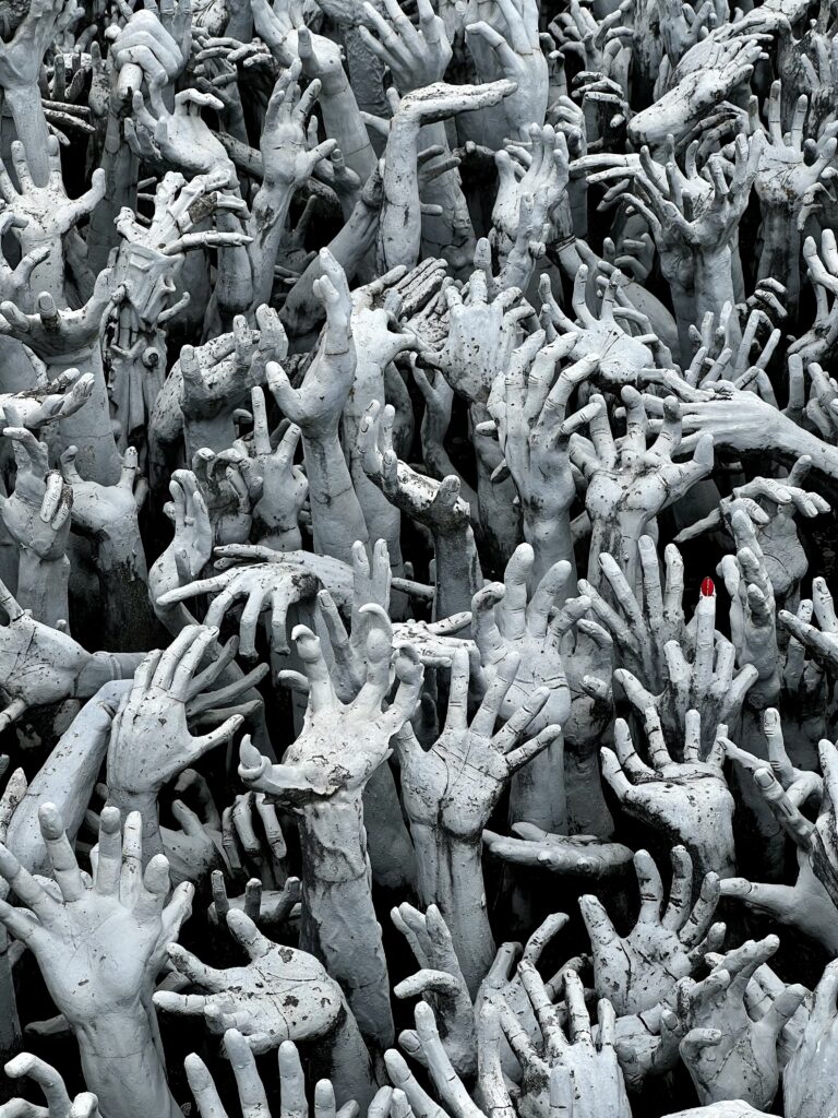 Travel Photo: Outstretched hands scultpure below the Bridge of the Cycle of Rebirth at Wat Rong Khun in Thailand.